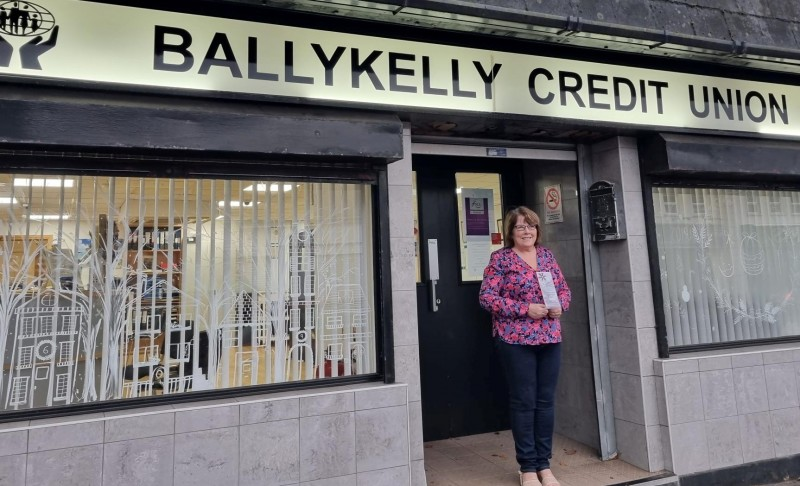 Ballykelly Credit Union staff member beside their winning Christmas windows displays