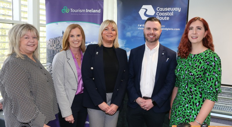 Council’s Tourism Team welcomed speakers from Tourism NI and Tourism Ireland to a recent event in Cloonavin. Pictured from (l-r) Esther Dobbin Region and Investment Manager at Tourism NI, Kerrie McGonigle Causeway Coast and Glens Borough Council Destination Manager, Nikki Paterson, Business Solutions Manager at Tourism NI, Mark McCrann Council’s Destination Marketing Officer and Natasha Johnston, Industry Liaison Executive at Tourism Ireland. The group are pictured standing in front of Visit Causeway posters.