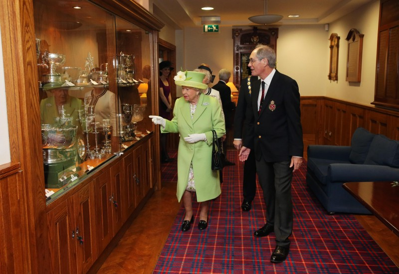 2016, The Queen admires the many trophies on display at Royal Portrush Golf Club.