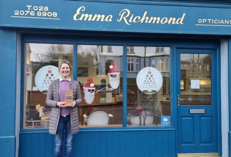 Emma Richmond of Emma Richmond Opticians, with her trophy for best Ballycastle Christmas Window in 2022, showing that Santa shops local and looks cool in his sunglasses