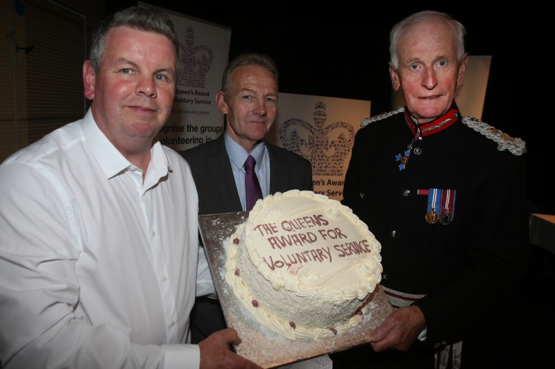 Phelim Curran from Curran Catering displays a special cake made for the occasion with Denis Desmond CBE and Boyd Douglas, Chairman of Burnfoot Community Association