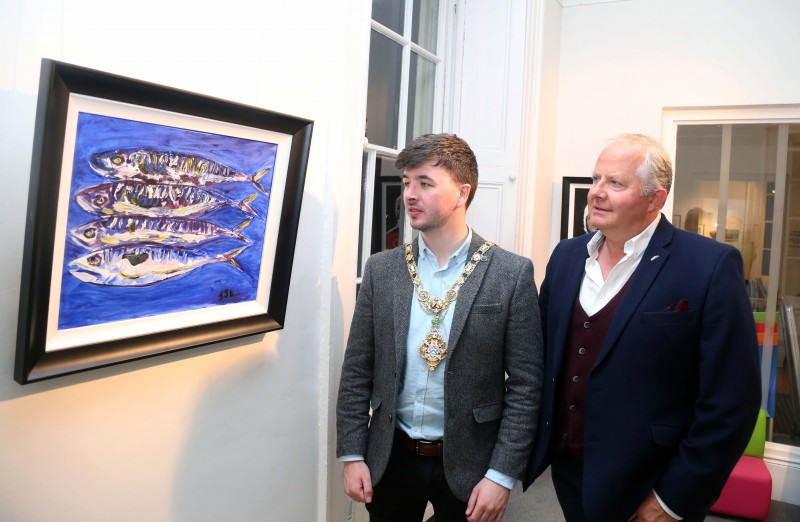 The Mayor of Causeway Coast and Glens Borough Council Councillor Sean Bateson pictured with artist Shane Laverty as they admire his painting ‘In Decline’.