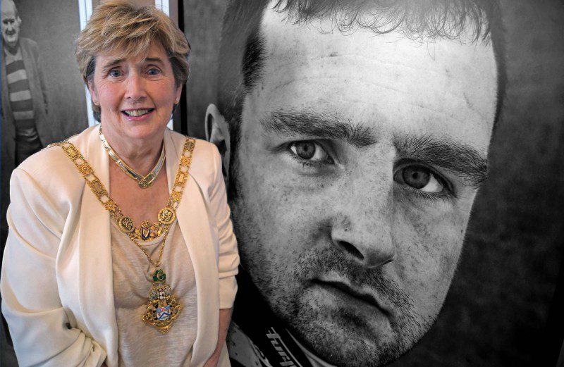 The Mayor of Causeway Coast and Glens Borough Council, Alderman Maura Hickey, with an image of Michael Dunlop in the background.