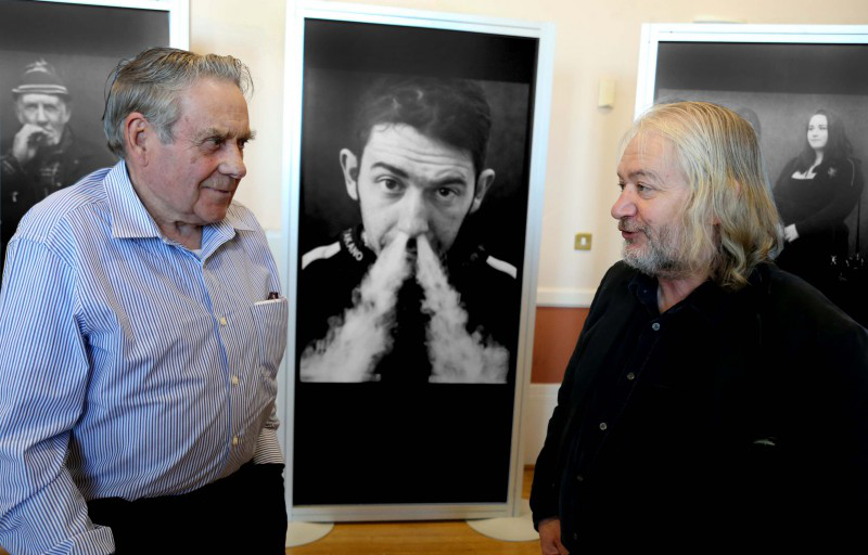 Jim Dunlop (right) pictured at the opening of the BBC Northern Ireland Road Racing People exhibition with Len Ireland.  A portrait of Jim's son Sam can be seen on the wall behind.