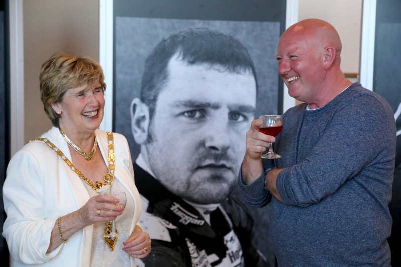 The Mayor of Causeway Coast and Glens Borough Council, Alderman Maura Hickey, and photographer Stephen Davison pictured in front of an image of Michael Dunlop featured in the exhibition.
