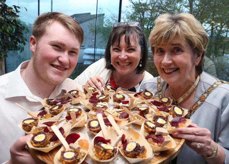The Mayor of Causeway Coast and Glens Borough Council pictured with Caroline Redmond from North Coast Walking Tours and Matthew Workman with the delicious Quail Breast and Black Pudding Quail Scotch Egg dish created by renowned chef Darran Benham, winner of the Year of Food and Drink Dish at IFEX 2016.