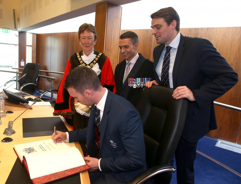 Richard Chambers signs the Freedom Register as the Mayor, Councillor Joan Baird OBE, Chief Executive David Jackson and Alan Campbell look on.