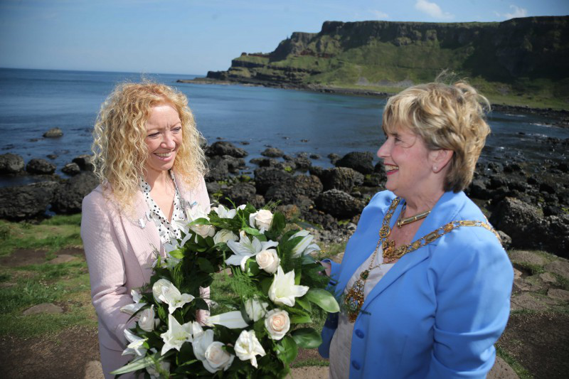 Lacada Point in the background as The Mayor of Sligo, Councillor Marie Casserly, and the Mayor of Causeway Coast and Glens Borough Council, Alderman Maura Hickey, prepare to lay a wreath at the Giant's Causeway to remember those who perished when La Girona sank at Lacada Point in 1588.