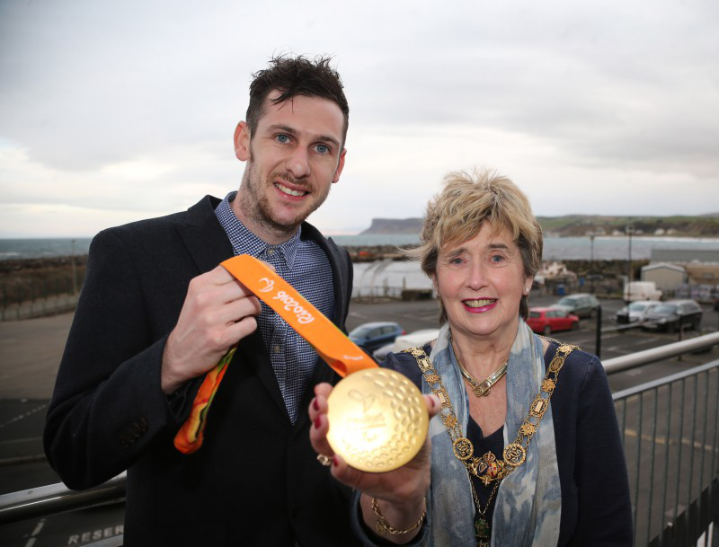 Michael shares one of his gold medals with the Mayor of Causeway Coast and Glens Borough Council, Alderman Maura Hickey.
