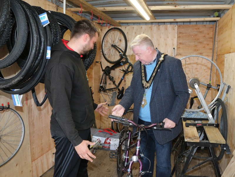 Mayor of Causeway Coast and Glens, Councillor Steven Callaghan is given an overview of how the bicycles are prepared for re-use by Men’s Shed Supervisor Jamie Vinnicombe