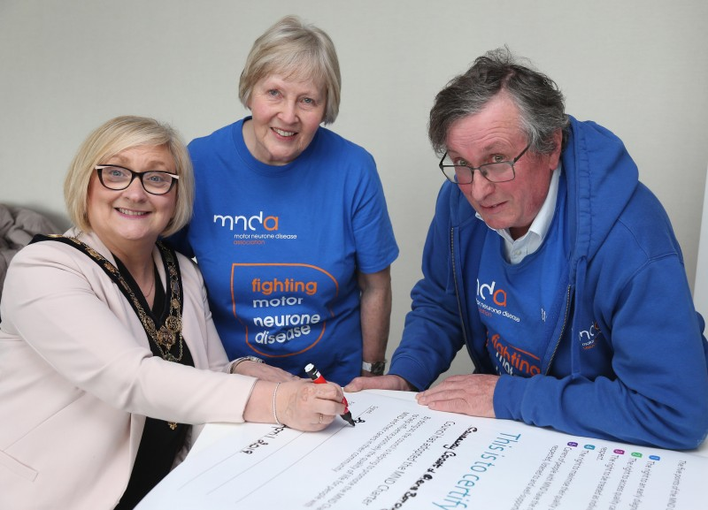 The Mayor of Causeway Coast and Glens Borough Council Councillor Brenda Chivers signs the motor neurone disease (MND) Charter as Stephen Thompson and Marie Holmes from the Motor Neurone Disease Association Northern Ireland look on.