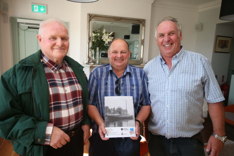 Jim Curry, Noel McCurdy and Brian McLarnon display the booklet which brings together Sam Henry's pictures of Rathlin Island and its people.
