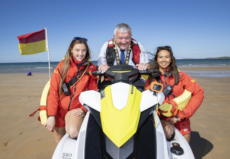 The Mayor of Causeway Coast and Glens Borough Council, Councillor Ivor Wallace, pictured at East Strand in Portrush with RNLI lifeguards Ellen Knox and Annie Jagoe.