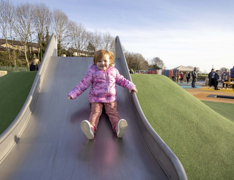 Three-year-old Lucy tries out the slide at Limavady Accessible Play Park.