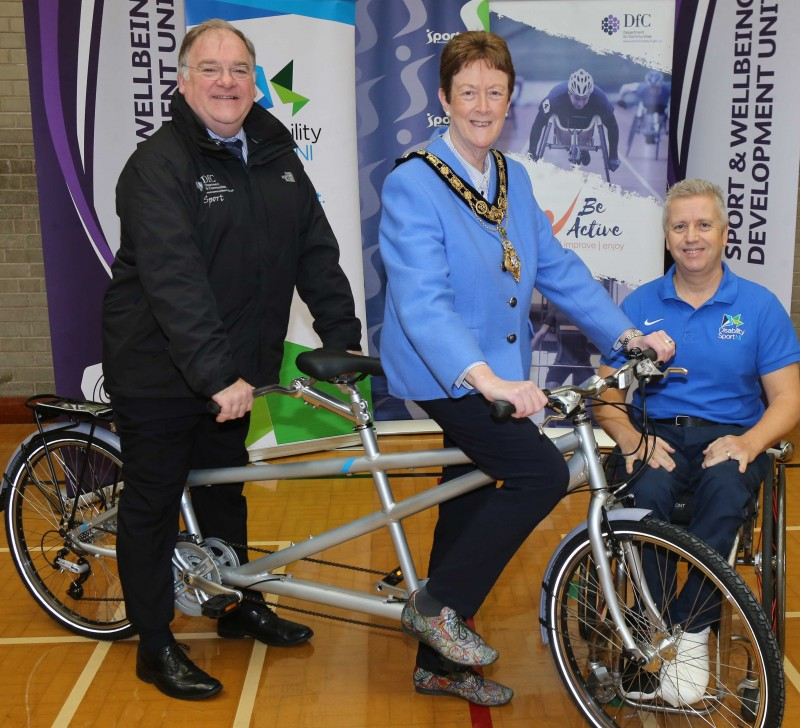 The Mayor of Causeway Coast and Glens Borough Council, Councillor Joan Baird OBE, tries out a tandem bike with Robert Heyburn from Department for Communities and Aubrey Bingham from Disability Sport NI.