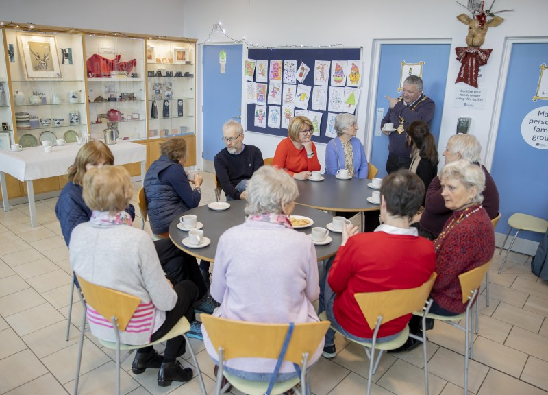 The Mayor of Causeway Coast and Glens Borough Council, Councillor Ivor Wallace, enjoys a cup of tea with an art class at Flowerfield Arts Centre in Portstewart, one of the Warm Welcome Spaces included in the new directory.
