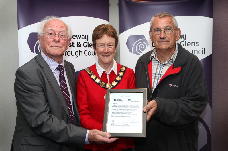 The Mayor of Causeway Coast and Glens Borough Council, Councillor Joan Baird OBE displays the signed Memorandum of Understanding with Reverend Terry McMullan, Chair of the Zomba Action Project and Paul Snelling, Secretary.