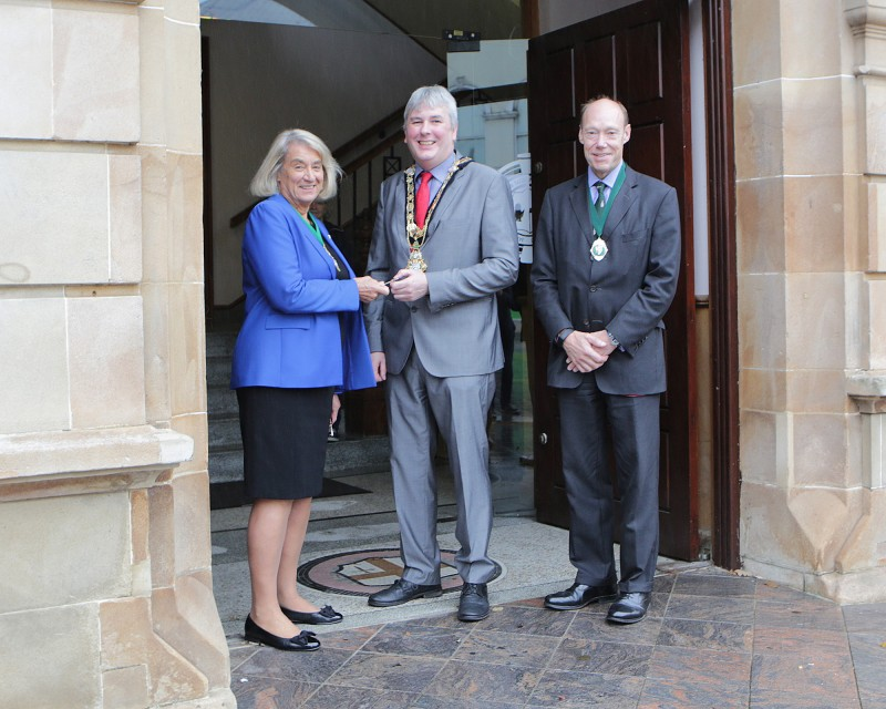 Mrs Wendy Hyde, Deputy Governor of The Honourable The Irish Society, gives the key of Coleraine Town Hall to Councillor Richard Holmes, Mayor of Causeway Coast and Glens Borough Council, marking its official handover along with Edward Montgomery, Secretary of The Honourable The Irish Society.