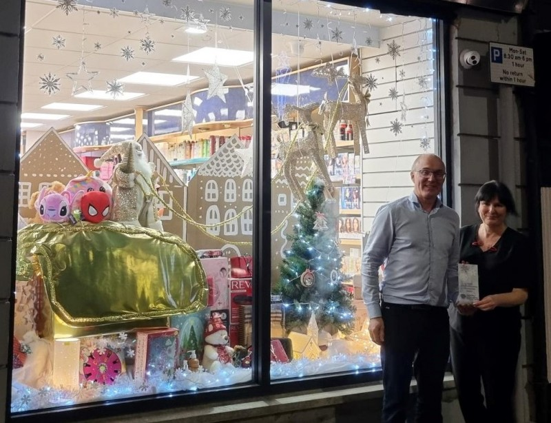 Shield Pharmacy’s staff members standing beside their festive window dressing.