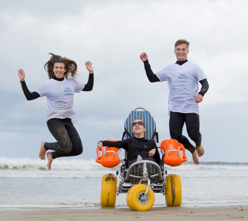 Mae Murray Foundation volunteers Molly Fekkes and Morgan Wharry celebrate the arrival of the new  equipment at Benone beach with 18 year old Talia McDowell.