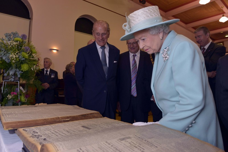 2014, The Queen and Prince Philip look archive newspaper editions of the Chronicle/Constitution.