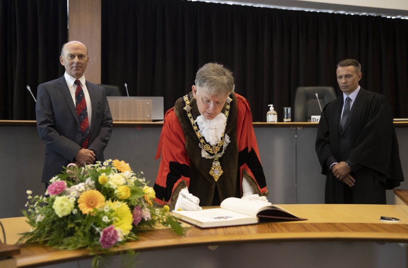 The Mayor of Causeway Coast and Glens Borough Council Alderman Mark Fielding signs the Honorary Burgess register as Dr Ian Kerr, Captain of Royal Portrush Golf Club and Council Chief Executive David Jackson look on during the Freedom of the Borough ceremony held in Cloonavin on Friday 21st May 2021.